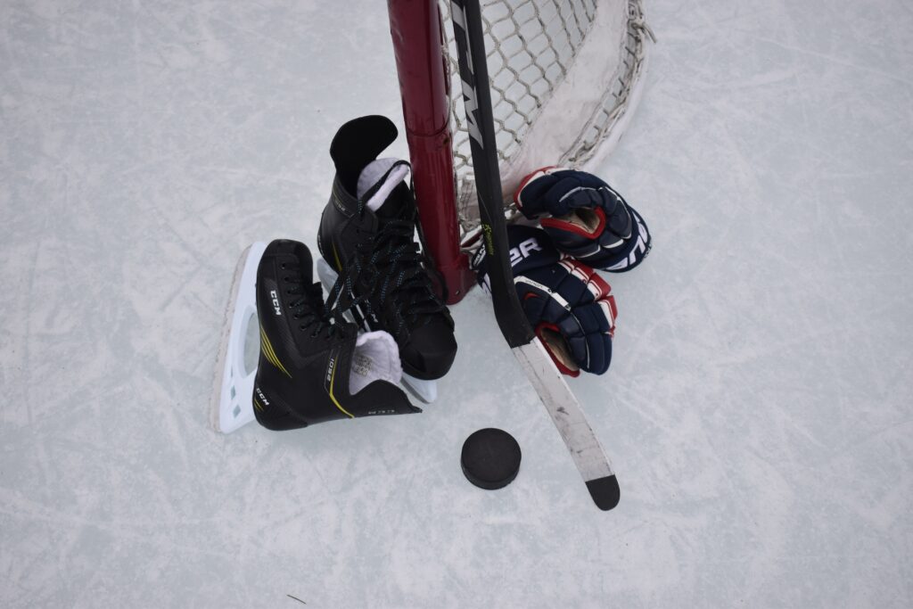 hockey skates and puck by a net