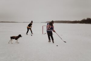 guys playing pond hockey with their dog