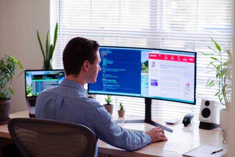 a man in front of 3 laptop screens designing a website