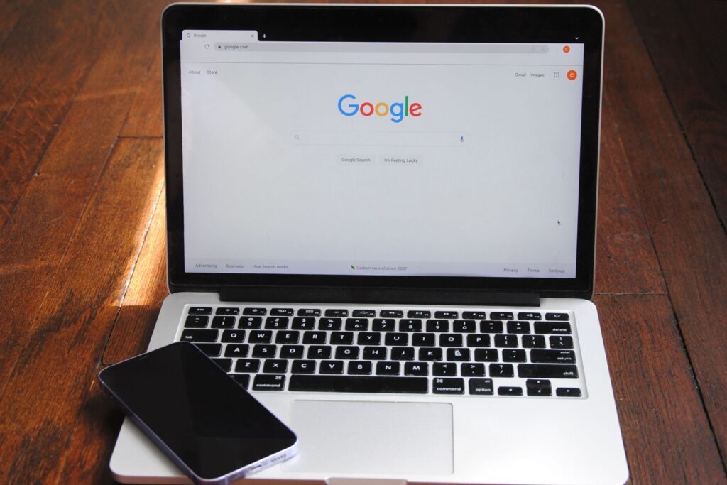 laptop with google home page and iphone on keyboard