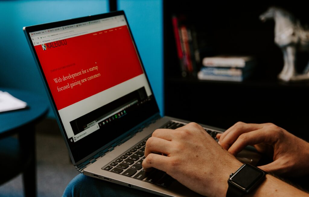 hands typing on laptop keyboard with red screen on